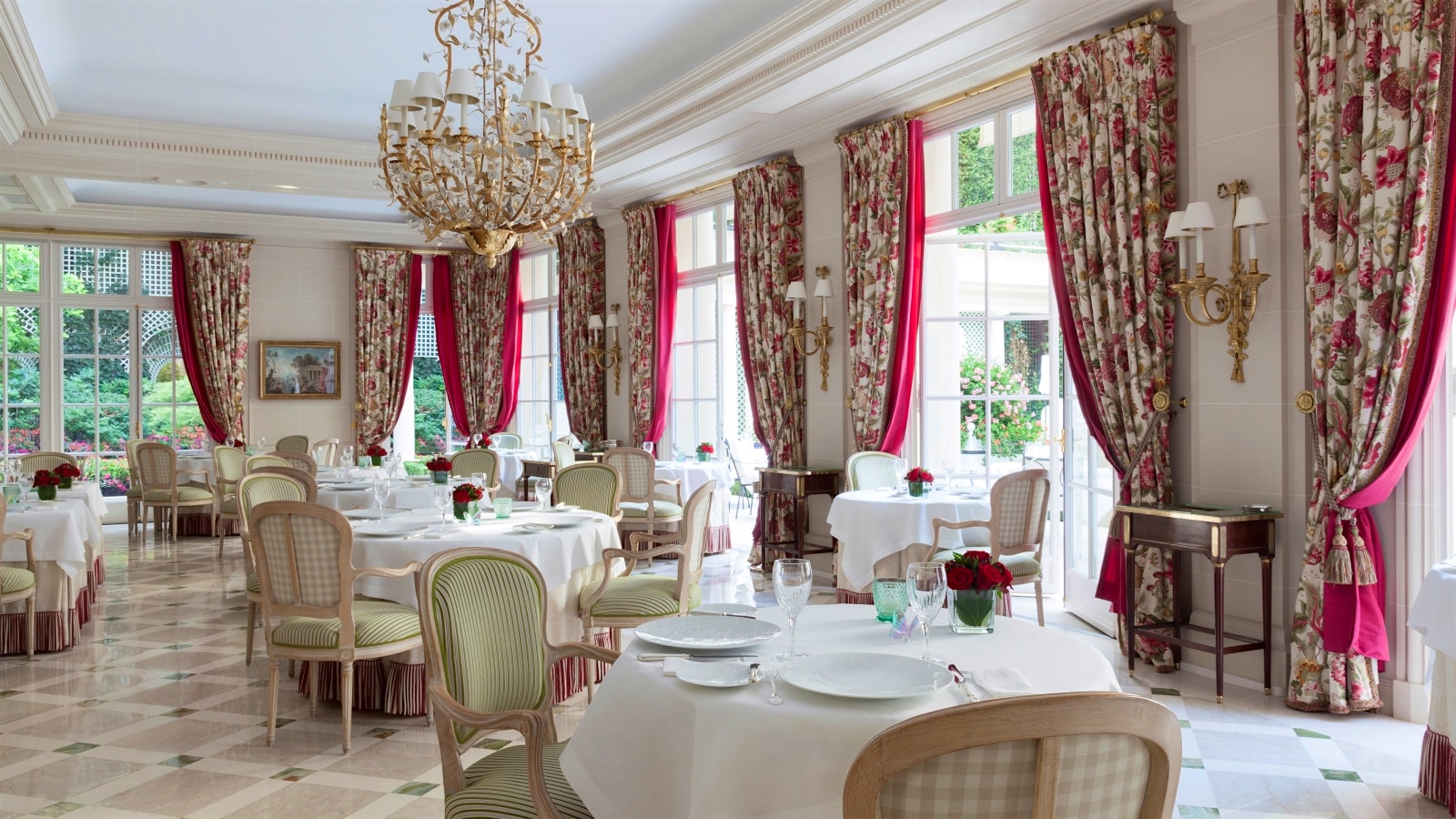 Tables in the dining room at Epicure, with chandeliers and a view of the garden